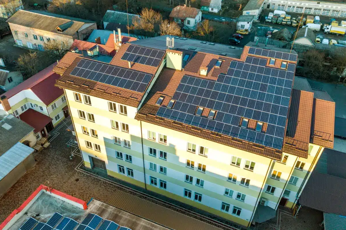 Vista aérea de un edificio residencial con paneles solares en el tejado, destacando la instalación de energía limpia y sostenible.