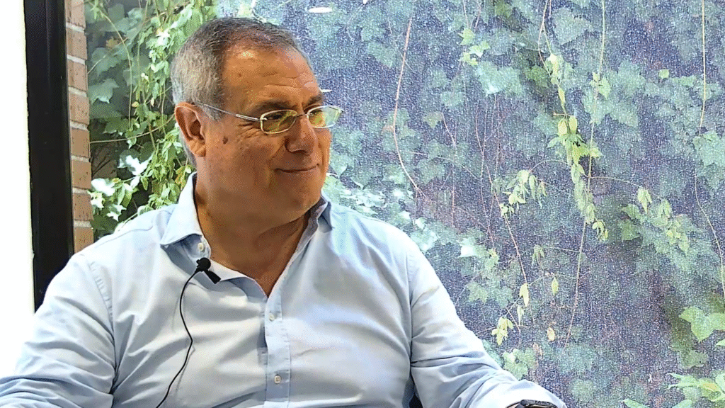 Luis Ortiz, Director Comercial de Perfecta Industrial (la división de Perfecta Energía dedicada a instalaciones solares industriales), en un entorno profesional, conversando mientras muestra una expresión amistosa y confiada; de fondo, se aprecia vegetación tras una ventana, transmitiendo calma y enfoque sostenible.