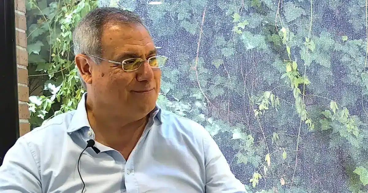 Luis Ortiz, Director Comercial de Perfecta Industrial (la división de Perfecta Energía dedicada a instalaciones solares industriales), en un entorno profesional, conversando mientras muestra una expresión amistosa y confiada; de fondo, se aprecia vegetación tras una ventana, transmitiendo calma y enfoque sostenible.