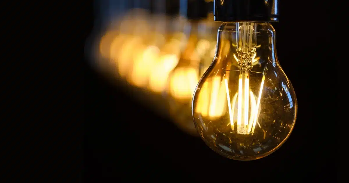 Primer plano de una bombilla iluminada con otras al fondo, metáfora de continuidad eléctrica con backup fotovoltaico