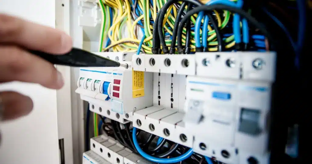 Técnico ajustando un interruptor en el cuadro eléctrico, con cableado multicolor, durante la instalación de backup para autoconsumo