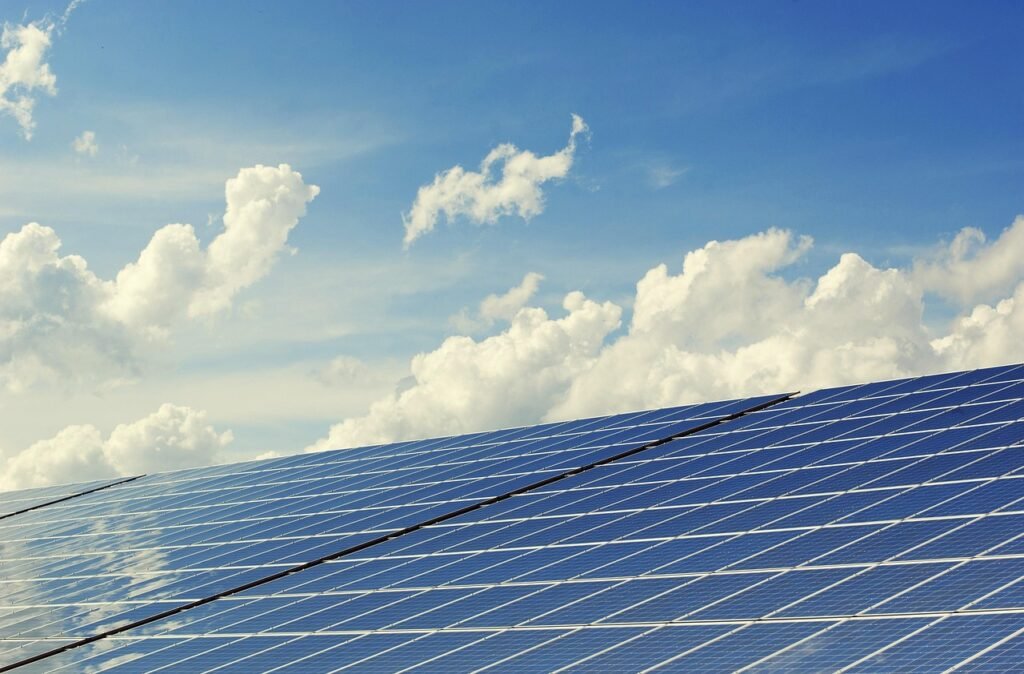 Placas solares en primer plano y cielo con nubes, símbolo de energía compartida
